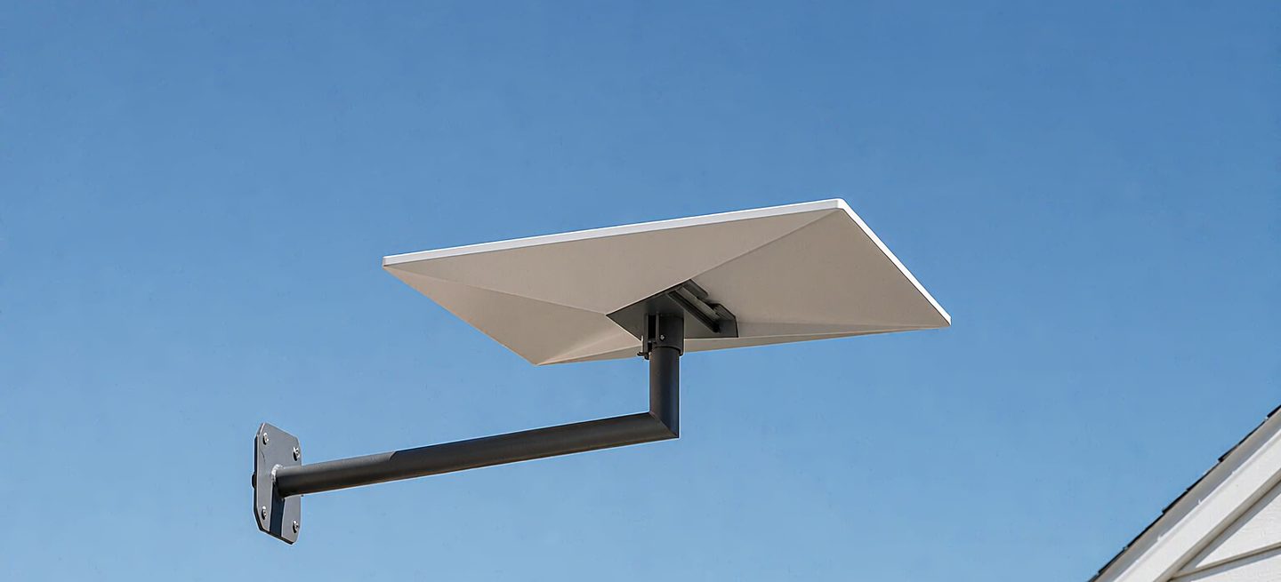 A Starlink dish on a wall bracket beside a house, clear of the roofline
